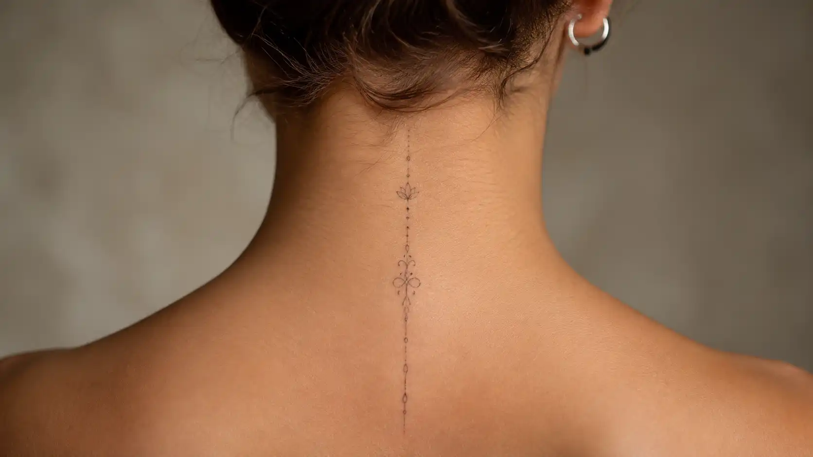 Close-up of the back of a woman's neck with a delicate fine-line tattoo