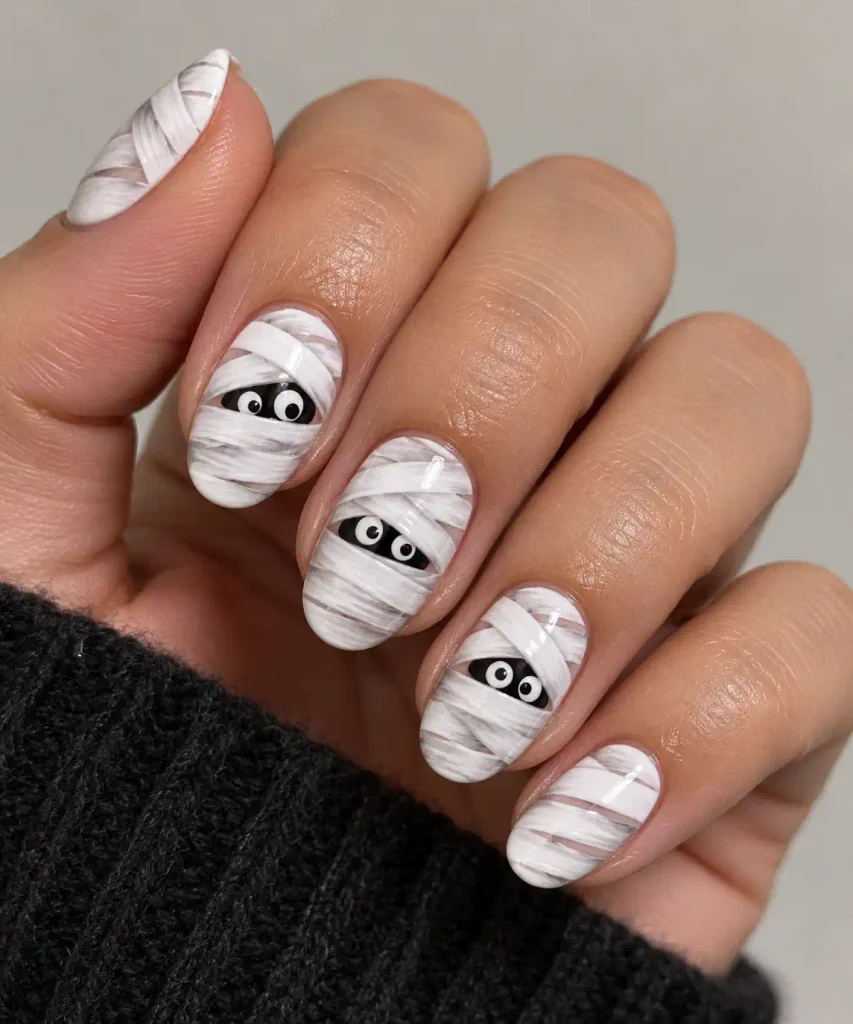 White mummy wrap nail art design with peeking eyes